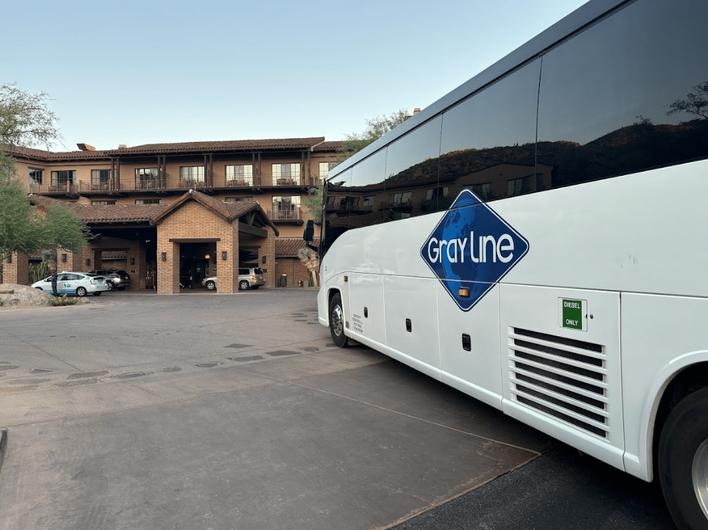 Gray Line charter bus parked in front of a luxury hotel, likely transporting guests to a food and wine festival in Scottsdale.
