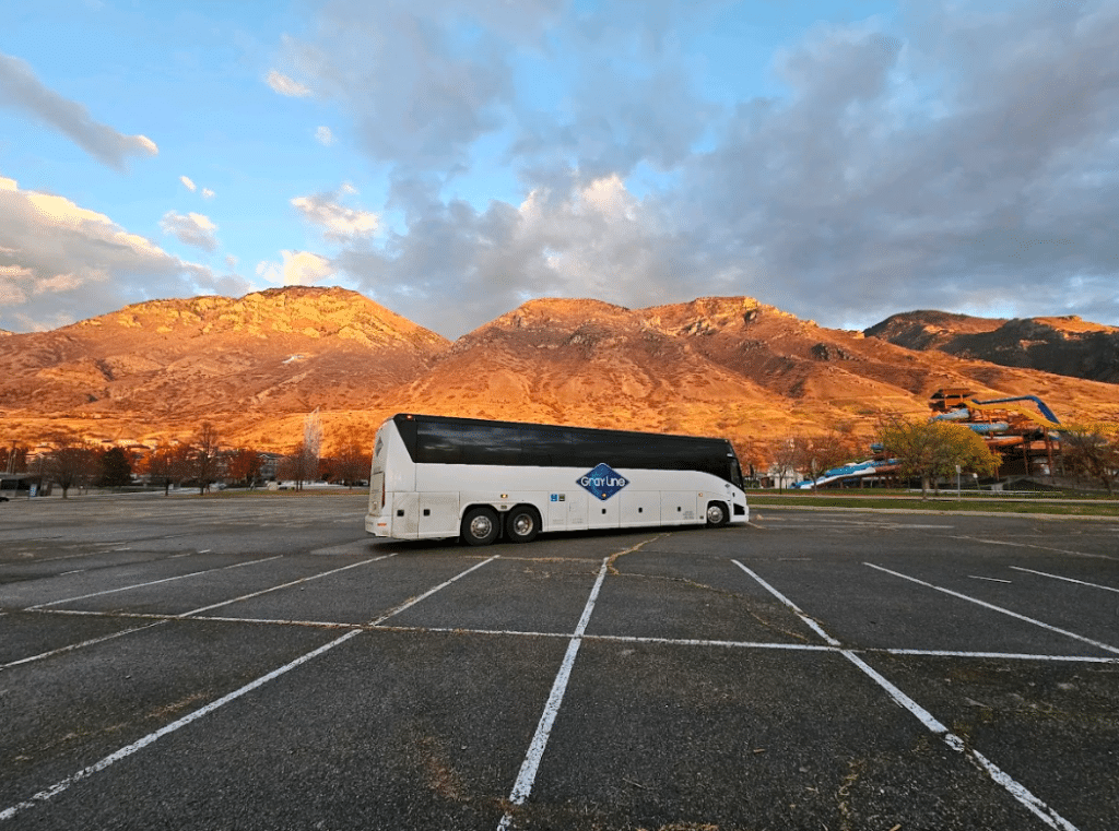 Gray Line bus parked in an empty lot with mountains in the background, perfect for a Tucson bus rental.