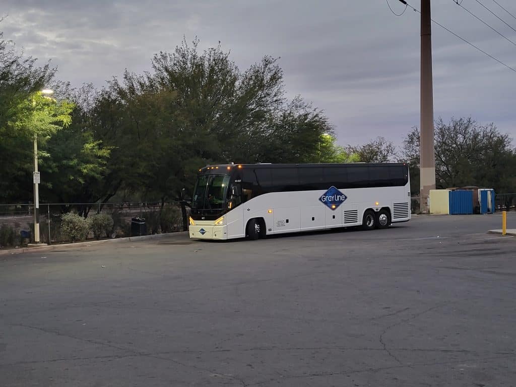 Gray Line Tours & Bus Rentals' bus parked on a parking lot near the fence